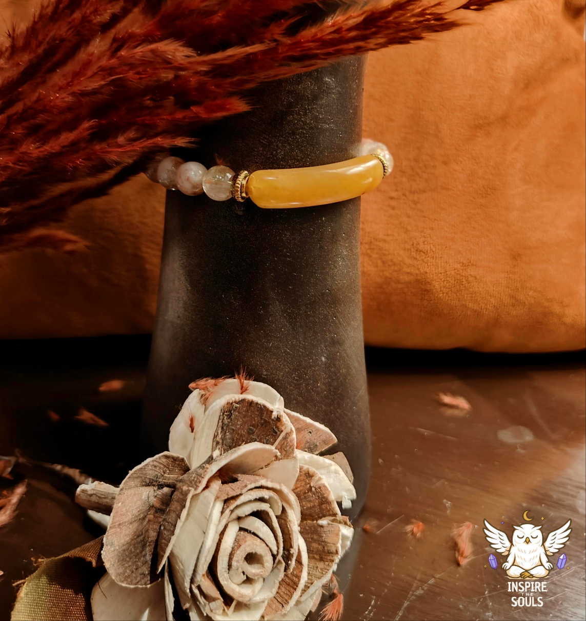 citrine crystal Bracelet with yellow stone on wrist, dried flower, and brown fabric background