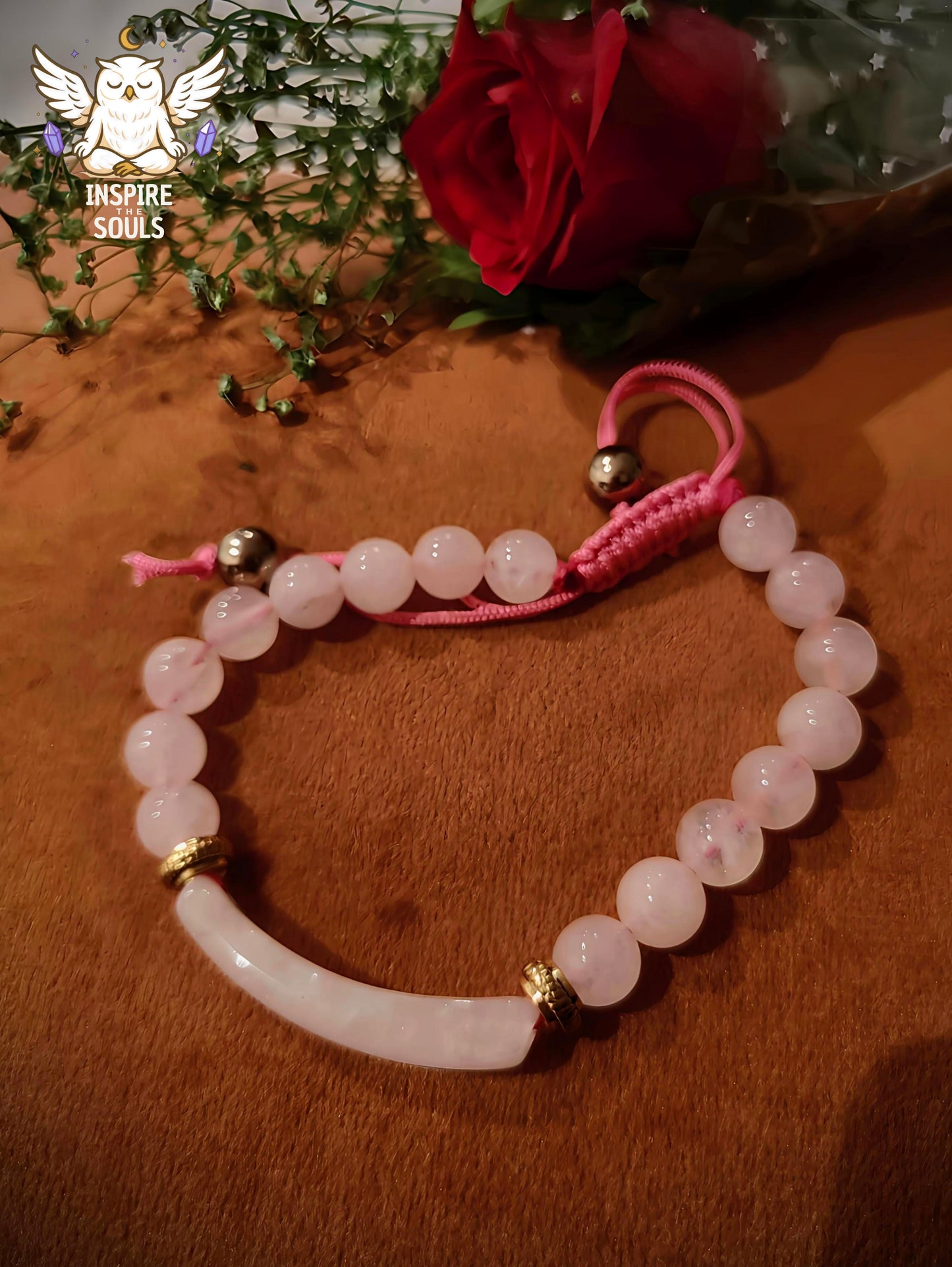 rose quartz Pink beaded bracelet with gold accents on a wooden surface, featuring a red rose and greenery.