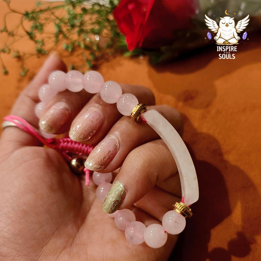 Hand holding a rose quartz soulstone series by Inspirethesouls bracelet with a white cord, against an orange background with a red rose.
